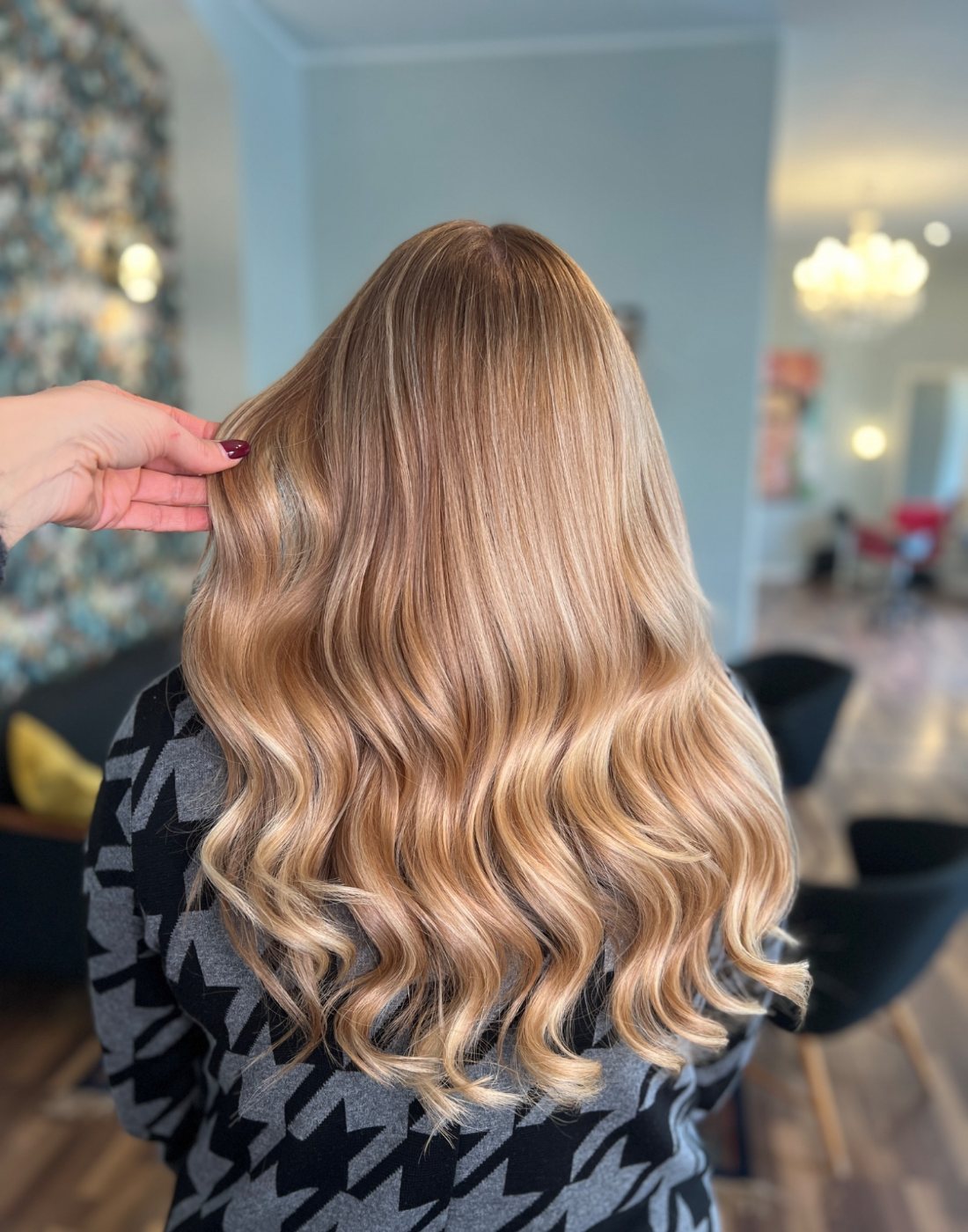 Lange blonde Wellen, von einer Hand sanft angehoben – Haarverdichtung bei Miss Lilly’s